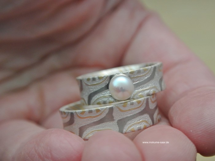 Mokume Gane Eheringe mit Perle in einer Hand